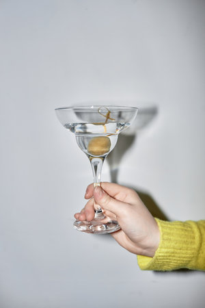 Minimal closeup of young woman holding martini glass during party, shot with flashの写真素材