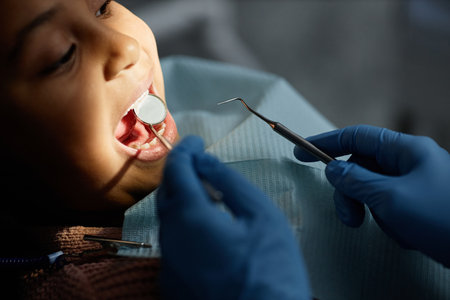 Closeup of little child in teeth checkup at dental clinic, unrecognizable dentist holding tools and mirror, copy spaceの写真素材