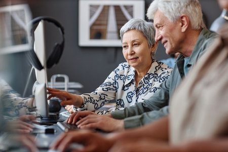 Portrait of senior man and woman looking at computer screen in technology class for senior people