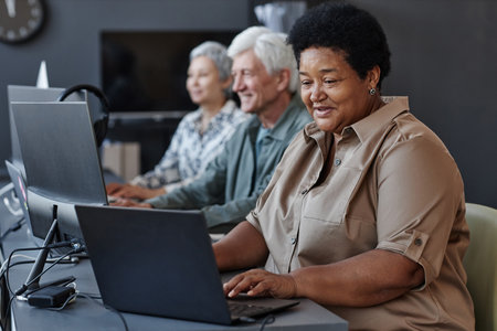 Portrait of senior black woman using computer and smiling in computer class for elderlyの写真素材