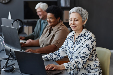 Side view portrait of senior Asian woman using computer in programming class for seniorsの写真素材