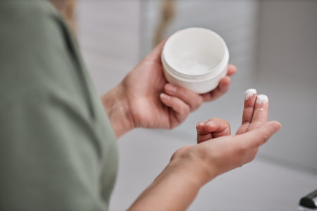Closeup of senior woman holding can of face cream during skincare routine in morning, copy spaceの写真素材