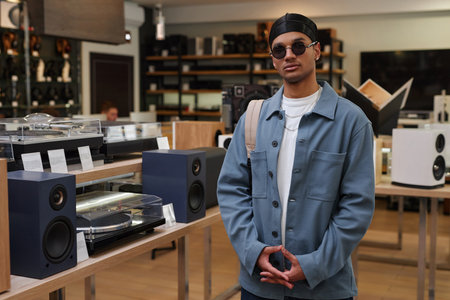 Portrait of black young man wearing stylish outfit standing in music store and looking at camera, copy spaceの写真素材