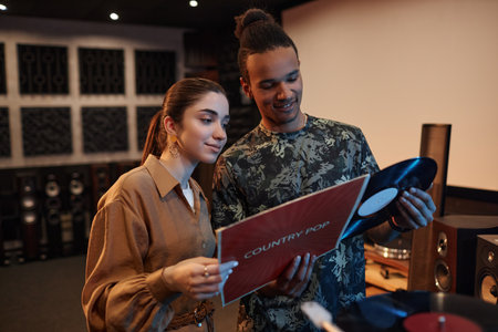 Waist up portrait of young couple holding vnyl records while enjoying music evening at homeの写真素材
