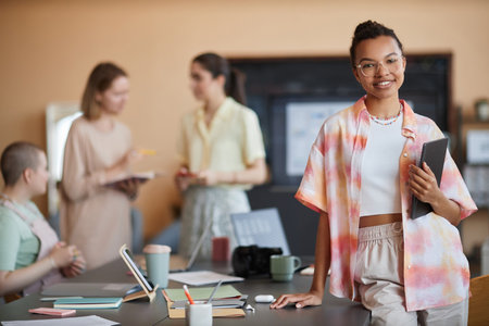 Waist up portrait of young black woman wearing smart casual style and looking at camera in team meeting setting at office, copy spaceの写真素材