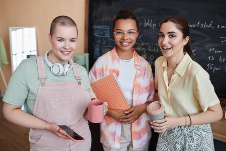 Waist up portrait of diverse team of three young women smiling at camera standing in modern officeの写真素材