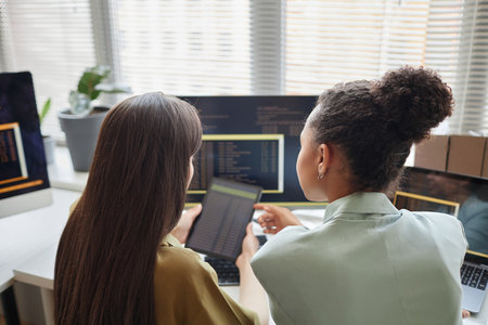 Back view at two young women holding digital tablet with codeの写真素材