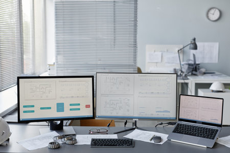 Background image of engineers workplace in office with plans and blueprints on multiple computer screens, copy spaceの写真素材