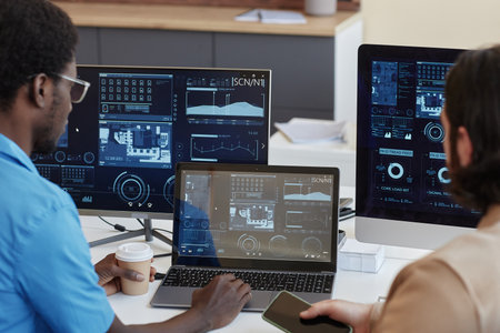 Focus on laptop with statistic graphic data on screen and young African American IT manager and his...