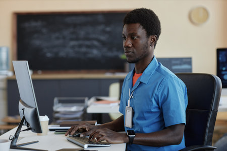 Young programmer concentrating on creative work or new project while sitting by desk in front of...