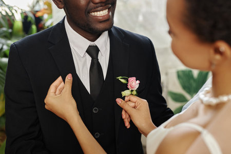 Closeup of black young couple getting married with bride adjusting jacket and boutonniere, copy spaceの写真素材
