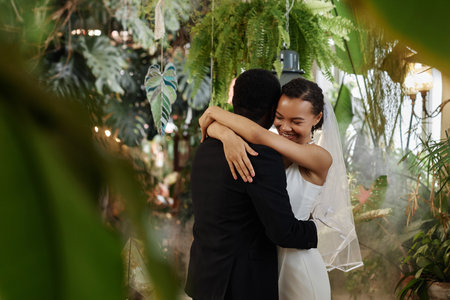 Waist up portrait of young black couple getting married and dancing together in orangerie full of lush tropical plants, copy spaceの写真素材