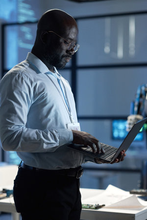 Vertical image of African American engineer using laptop at his work in officeの写真素材