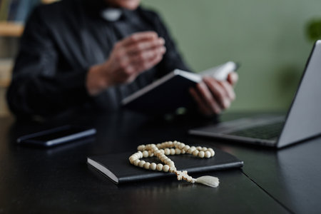 Close up of rosary on workplace desk with unrecognizable priest in background, copy spaceの写真素材