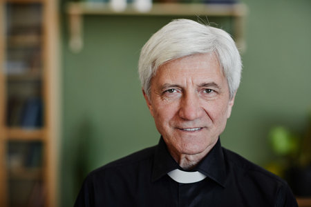 Close up portrait of white haired senior priest smiling at camera in office setting, copy space