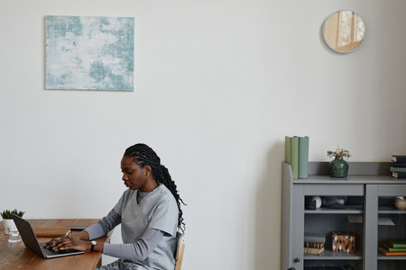 Portrait of young black woman as female nurse using laptop at desk, copy space
