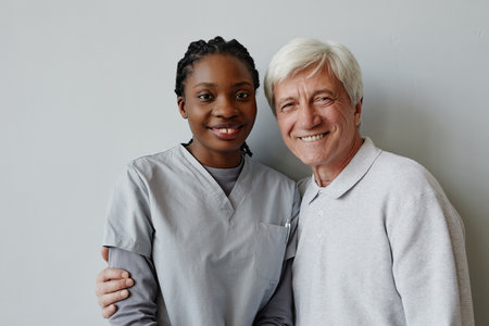 Waist up portrait of black young woman as nurse and senior man smiling at camera togetherの写真素材