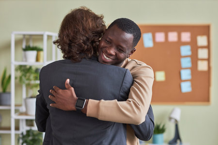 Portrait of black young man hugging colleague in office as friendly greeting, copy spaceの写真素材