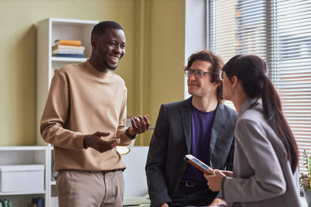 Waist up portrait of diverse young business team talking animatedly in office discussing work projectの写真素材