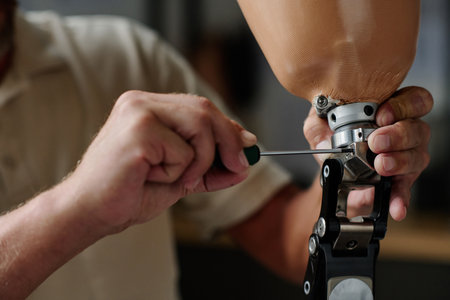 Closeup of unrecognizable male technician screwing knee joint in leg prosthetics, copy space