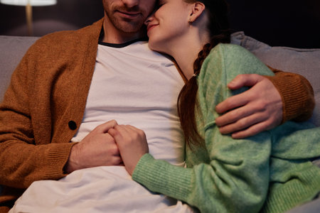 Closeup of young couple embracing affectionately enjoying time together at homeの写真素材