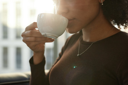 Close up of young black businesswoman enjoying cup of coffee in luxury office, copy spaceの写真素材