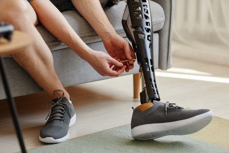 Close up of unrecognizable man putting on prosthetic leg indoors, copy space