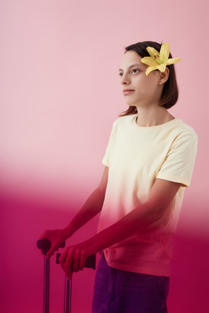 Two tone portrait of young girl with cerebral palsy standing against pink background in studio and...