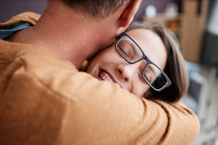 Candid closeup of teenage girl with cerebral palsy embracing father and smiling happily