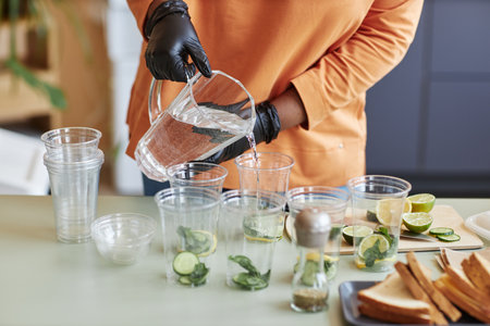 Closeup of cafe worker pouring sparkling water into lemonade glasses serving refreshing drinks, copy spaceの写真素材