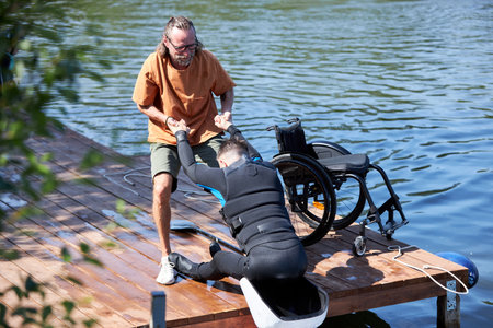 Portrait of senior sports instructor assisting man with disability using adaptive equipment for...
