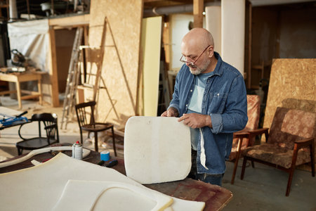Portrait of experienced senior artisan working on furniture refurbishing in workshop, copy spaceの写真素材