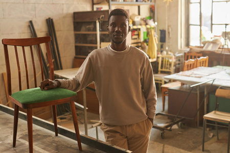 Warm toned portrait of young African American man looking at camera in workshopの写真素材