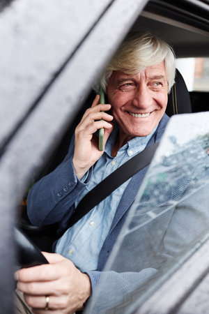 Vertical portrait of smiling white haired senior man speaking by phone inside carの写真素材