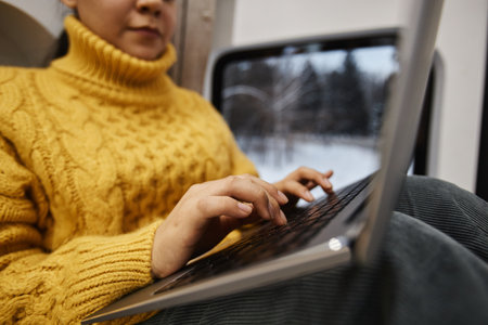 Close up of young woman using laptop in trailer van with focus on female hands typing, copy spaceの写真素材