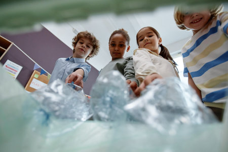 Diverse group of children putting plastic bottles into recycling bin POVの写真素材