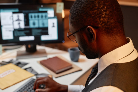 Close up of Black man as police detective using computer at workplace in office, copy spaceの写真素材