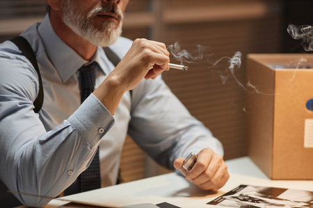 Close up of mature male detective smoking cigarette in police office, copy spaceの写真素材