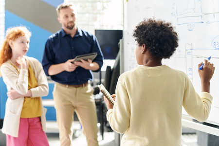 School kid answering questions of science teacher and writing on whiteboard