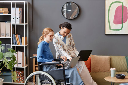 Colorful portrait of two young female professionals working with laptops in office, copy space