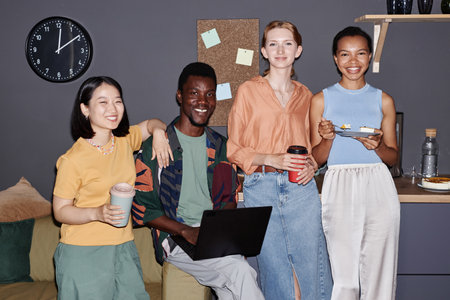 Diverse group of young professionals enjoying work in in office and looking at camera, shot with...