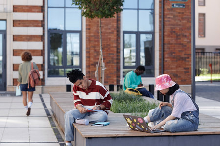 Diverse group of young people as students doing homework outdoors in park on college campus, copy...