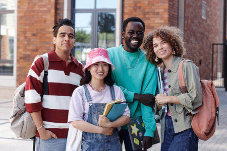 Waist up portrait of diverse group of students smiling at camera outdoors on college campusの写真素材