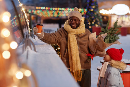 Portrait of happy father and daughter buying drinks at food truck in Christmas market