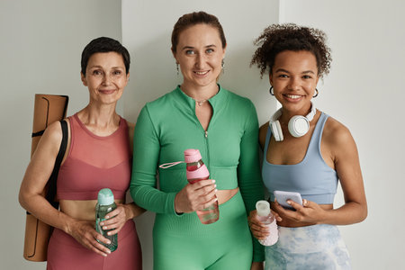 Diverse group of women wearing workout clothes and smiling at camera in gymの写真素材
