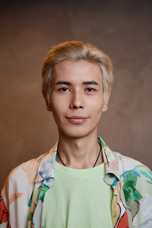 Vertical close up portrait of young Asian man with bleached hair looking at camera in studioの写真素材