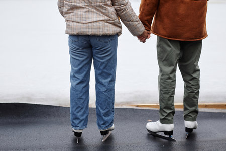 Back view of unrecognizable couple holding hands in ice skating rink, copy spaceの写真素材