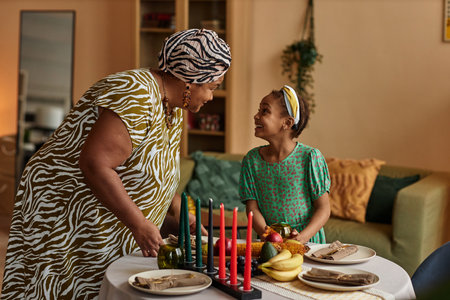 Black woman in traditional clothes explaining granddaughter origins of kwanzaa holidayの写真素材