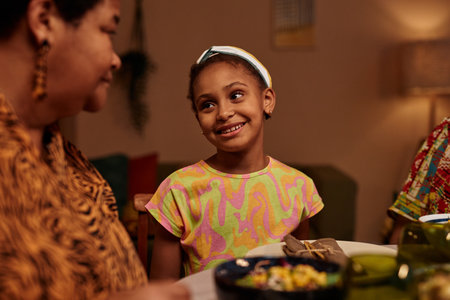 Portrait of smile preteen girl talking to mother at Kwanzaa family dinner