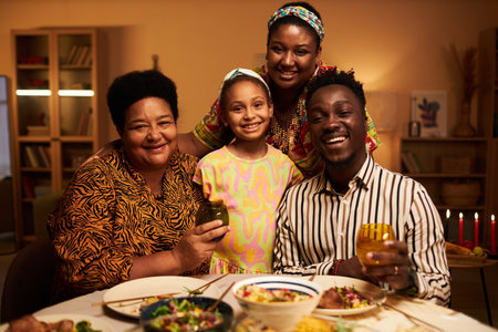 Happy grandmother, granddaughter and parents gathered at Kwanzaa dinner table